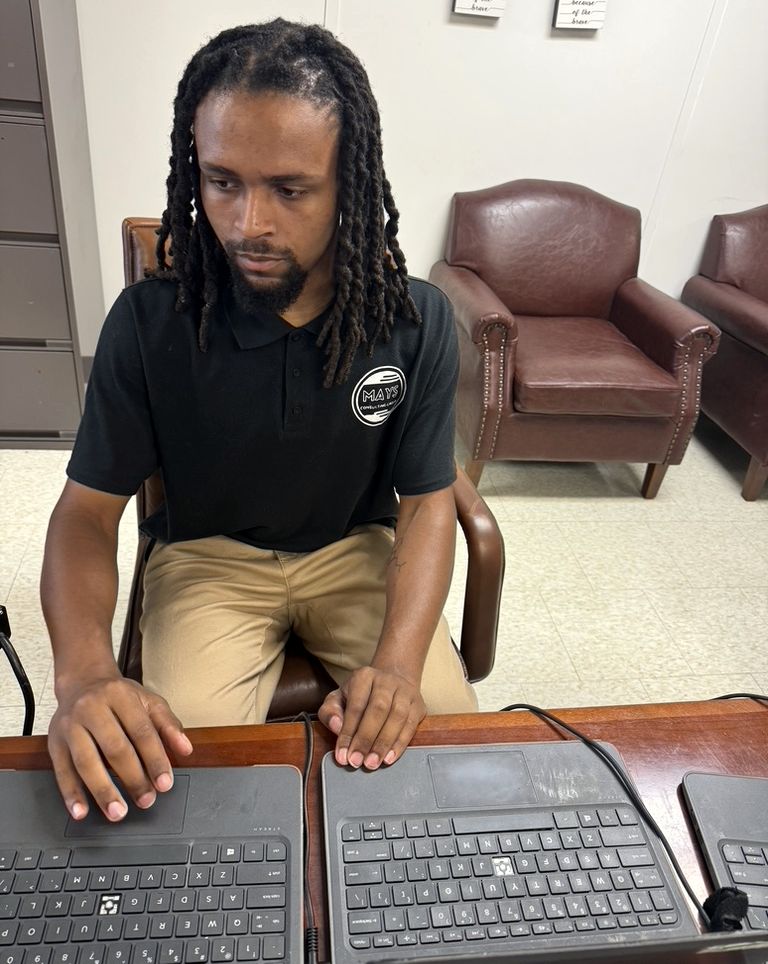 An MCG technician working across a row of student laptops