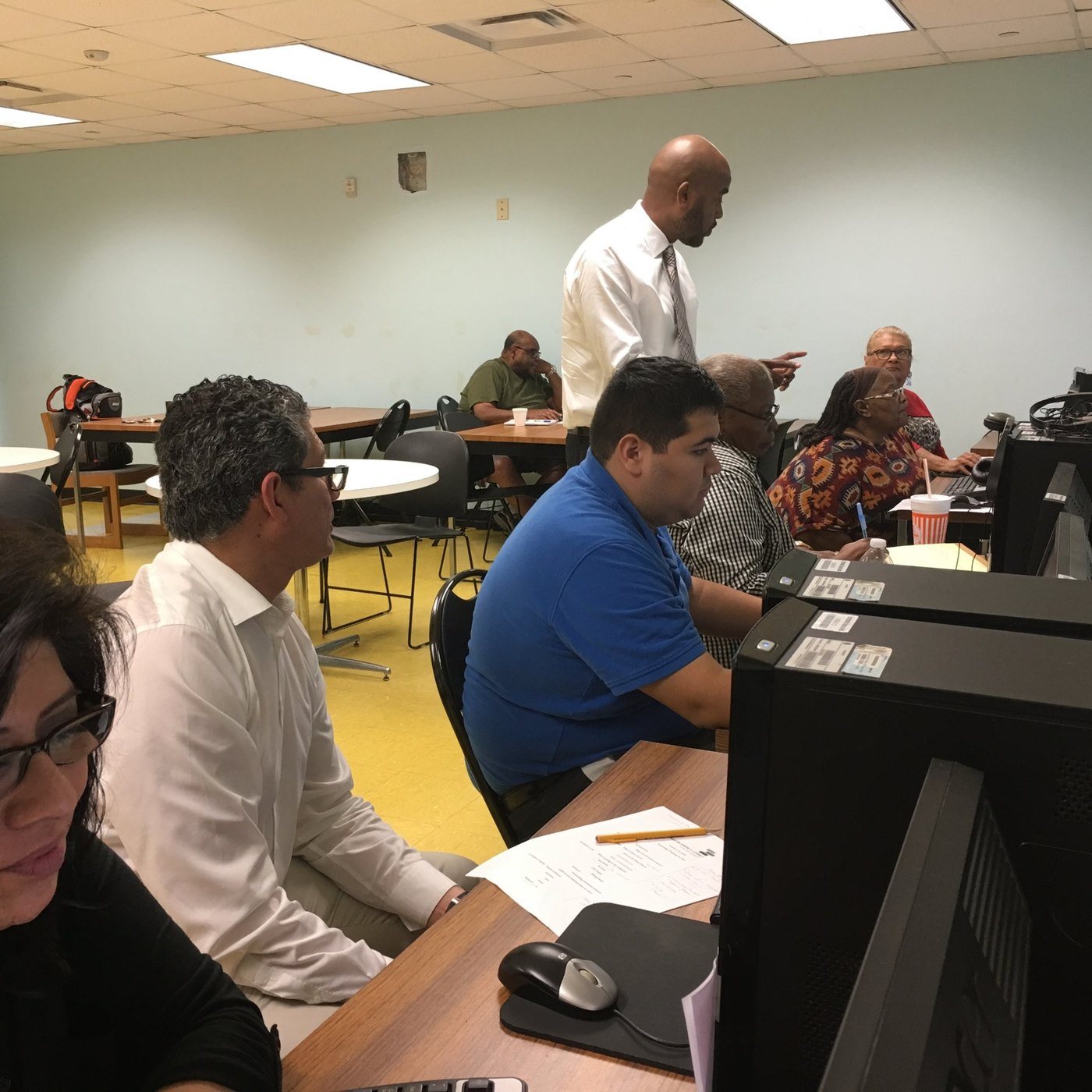 Jones standing over adults at the desktop computers: the home page, in the “small team you’ll know by name” section where the sound board photo is now. It shows him leading a training session.
