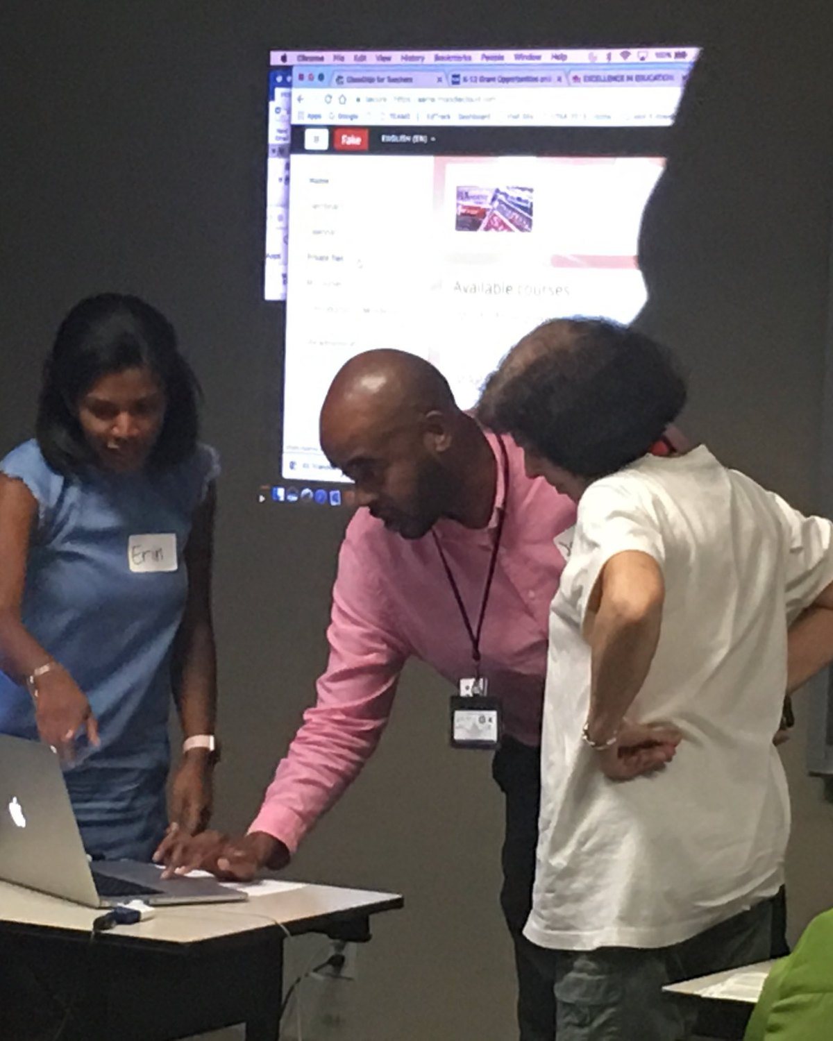 It shows hands-on support with real people, better than the repair shot there now. Caption: “Working through a new platform with teachers.”